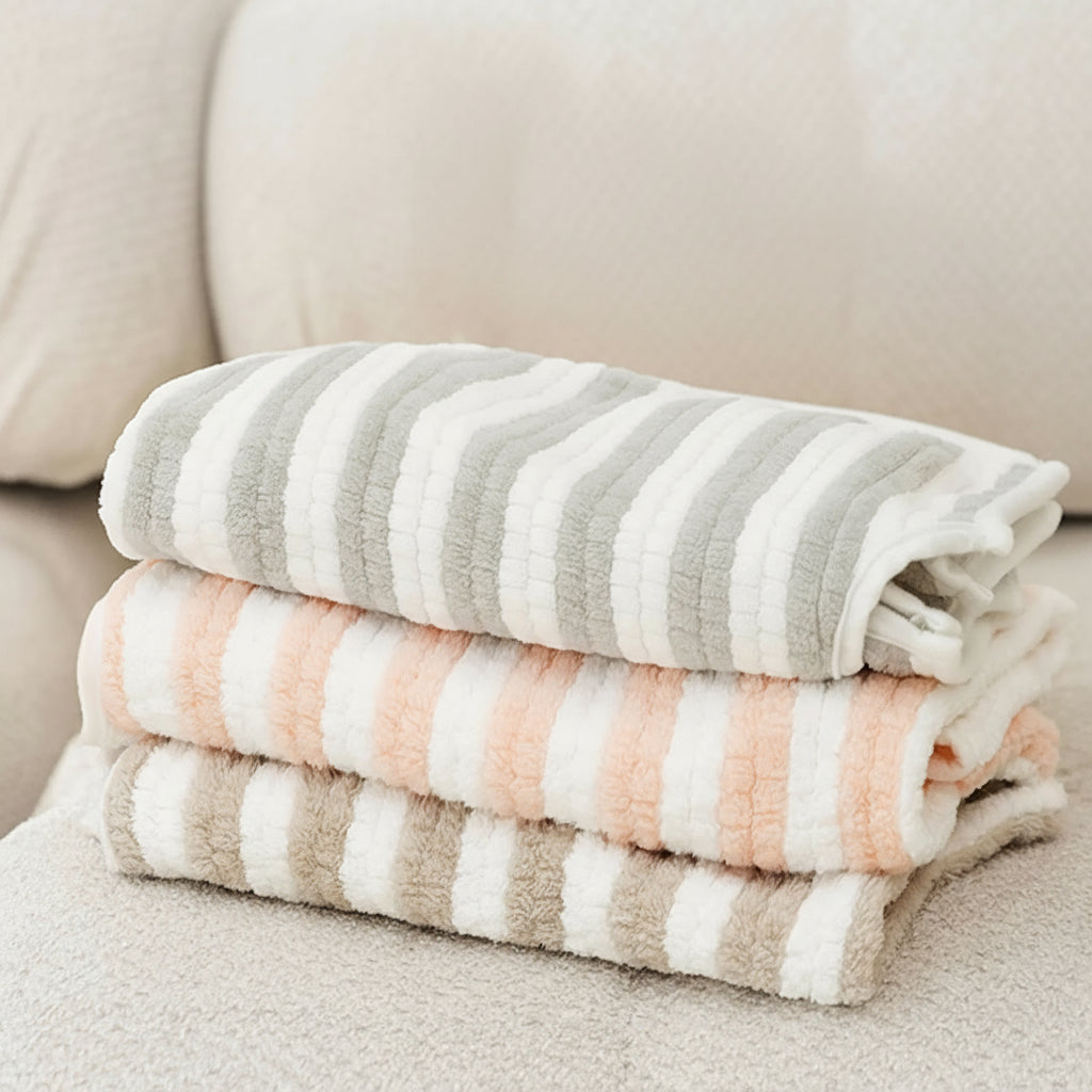 Stack of striped towels on a couch with antibacterial icons and text.